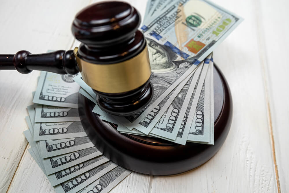 A gavel rests on a stack of $100 bills. How much money can you expect from a car accident settlement in California?